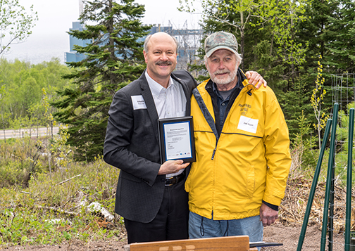 Al Hodnik holds a plaque given to Jack Rajala, chief executive of Rajala Companies, in appreciation of his work to restore the white pine to northern Minnesota.